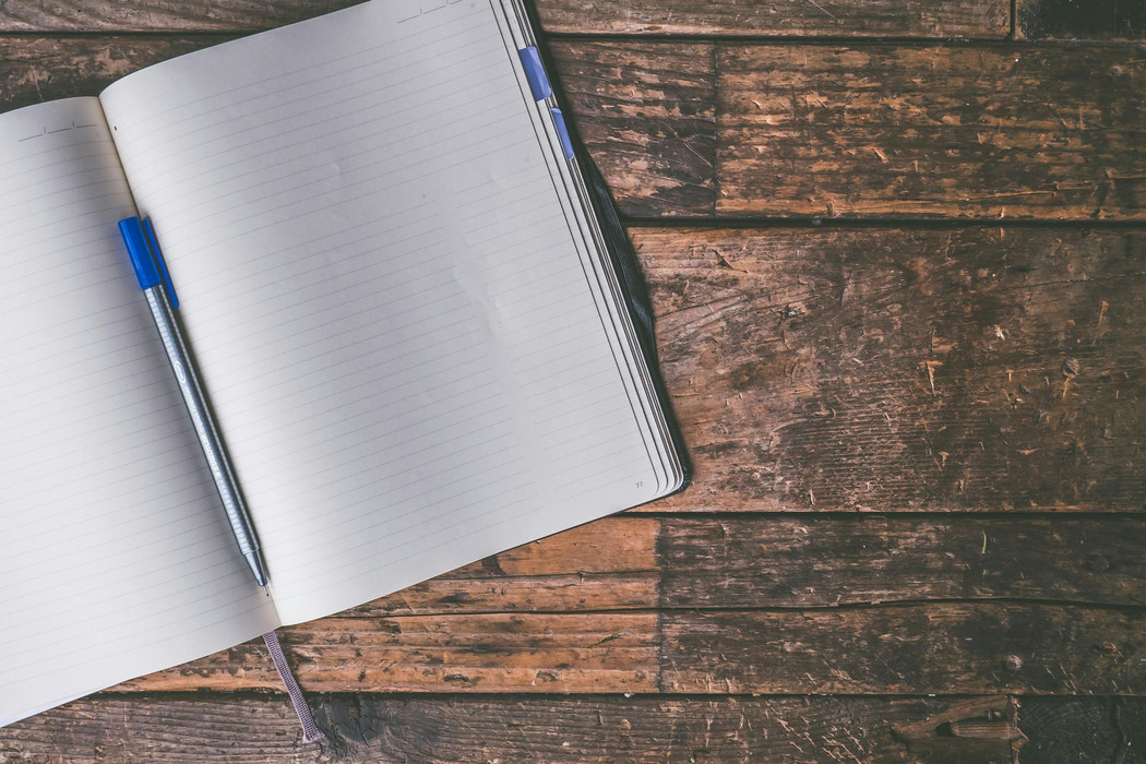 A pen in an open notebook with empty lined pages. 