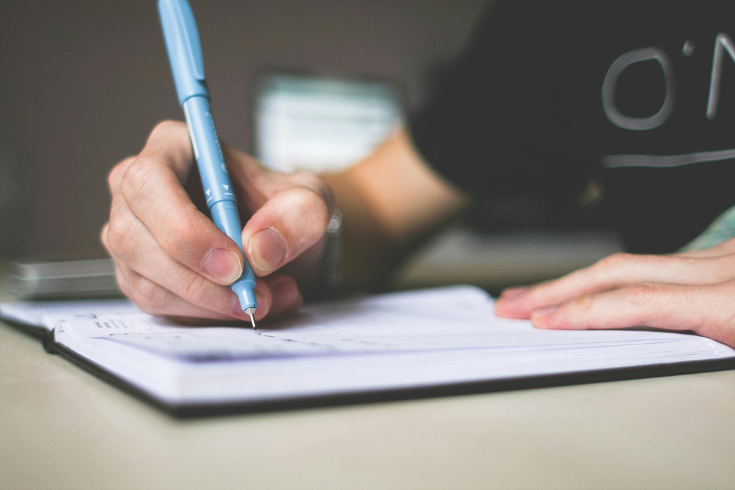 A close up photo of a hand holding a pen, writing. 