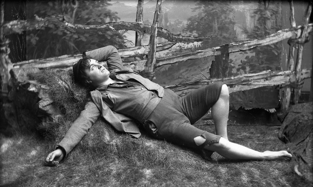 An actor portraying the fiction character Peer Gynt lying in the gras.